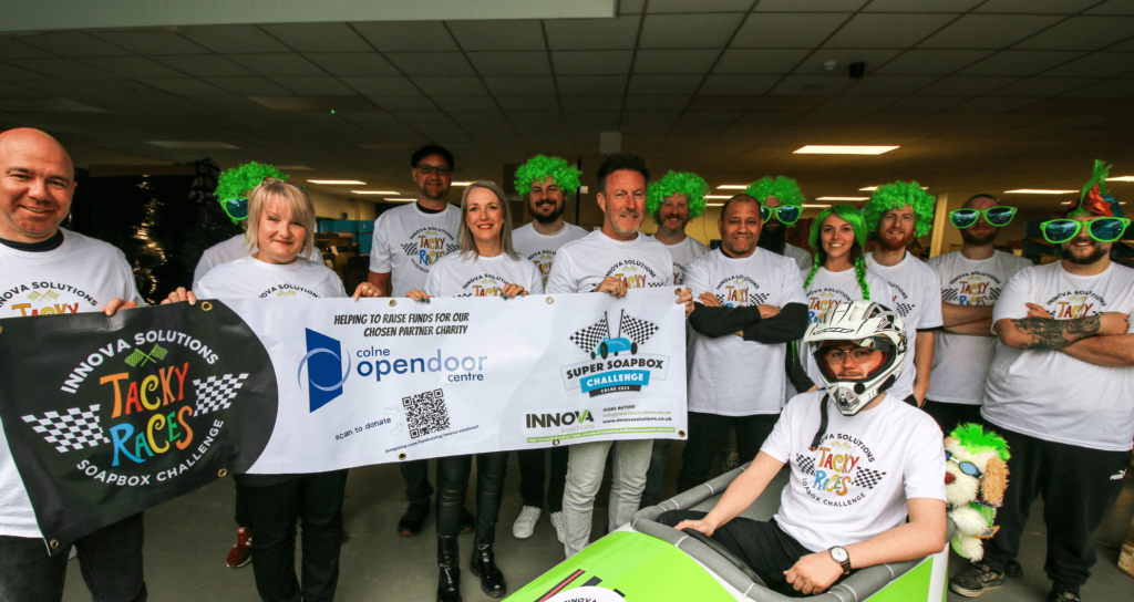 Innova Solutions team holding a banner in support of Colne Open Door. 
